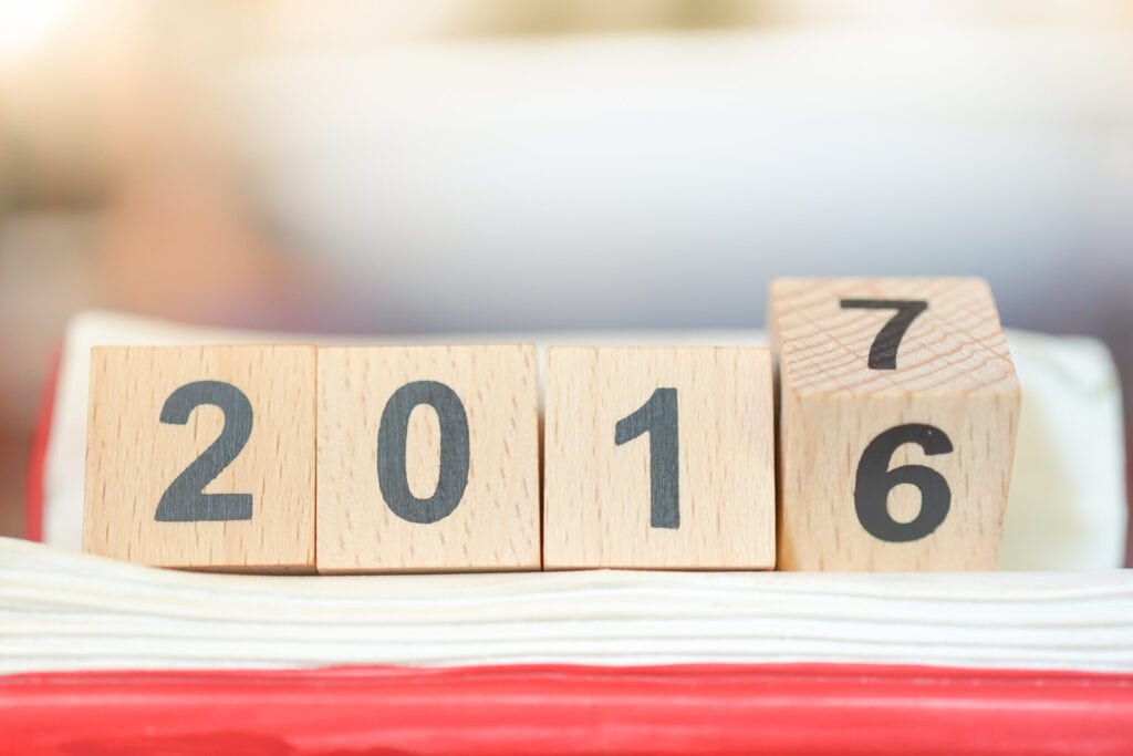 Wooden blocks displaying the year "2016" with the last block partly turned to reveal "2017" on a blurred background.