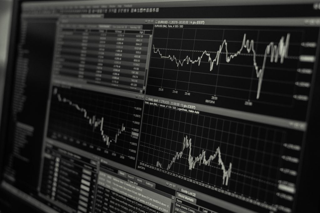 A computer screen displays multiple financial graphs and data tables, tracking stock market trends and performance indicators.