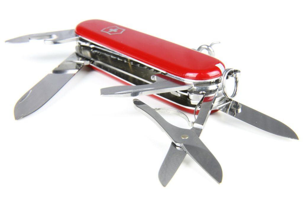 A red Swiss Army knife with multiple tools extended, including blades, scissors, and a small screwdriver.