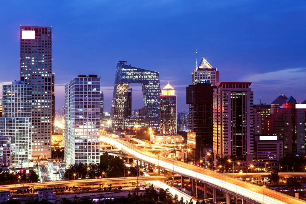 A city skyline at night with illuminated high-rise buildings and busy highways.