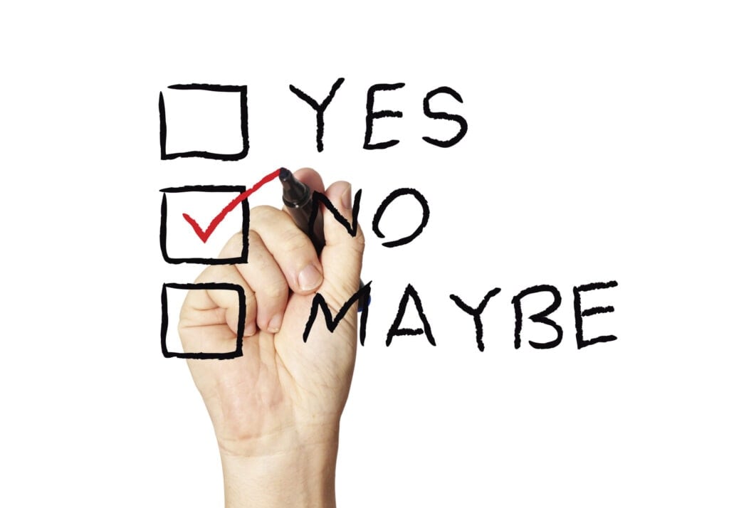 A hand is marking a checkbox with a red check next to "No" among three options: "Yes," "No," and "Maybe," written in black letters.