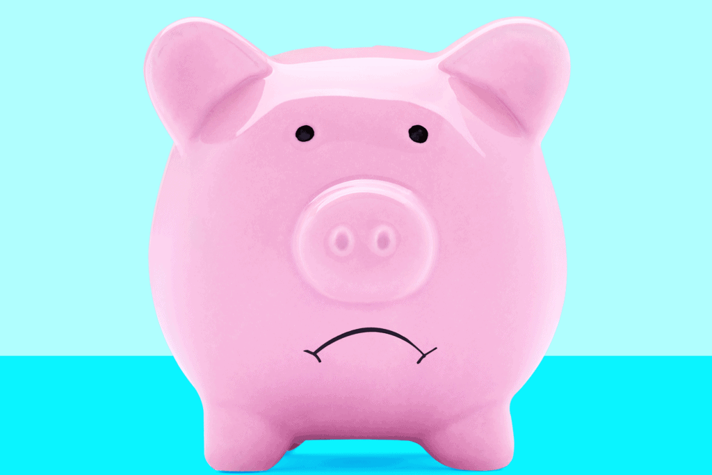 A pink piggy bank with a sad expression on a blue background.