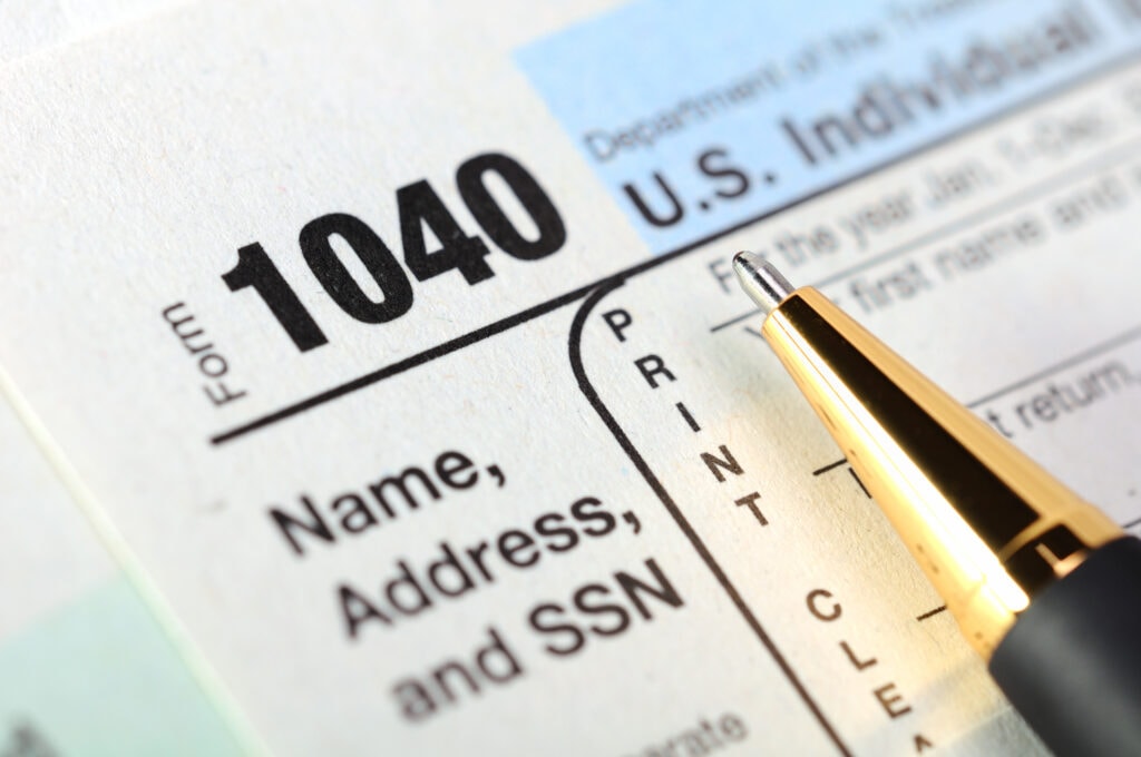 Close-up of IRS Form 1040 with a pen pointing at the area for name, address, and SSN.