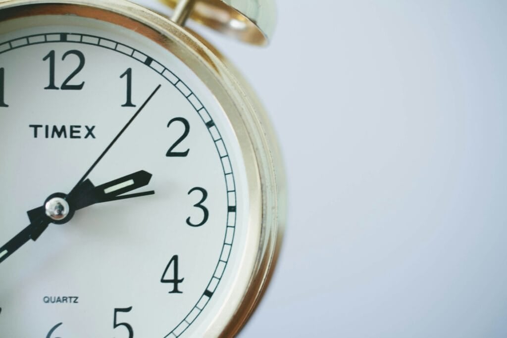 Close-up of a gold-framed analog clock showing the time as 10:11. The clock face features black hands, black numerals, and the word "Timex" printed on it.