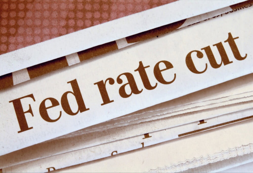 Close-up of a newspaper headline that reads "Fed rate cut." The text is printed in bold brown letters on a white background.