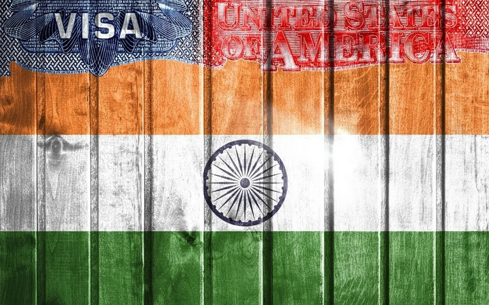 A wooden surface painted with the Indian flag, overlaid with images of a U.S. visa and the words "United States of America.