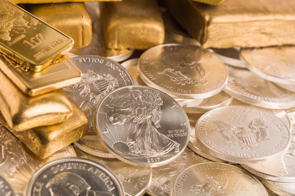Stacks of gold bars and American silver eagle coins are arranged together, displaying their detailed designs and shiny surfaces.