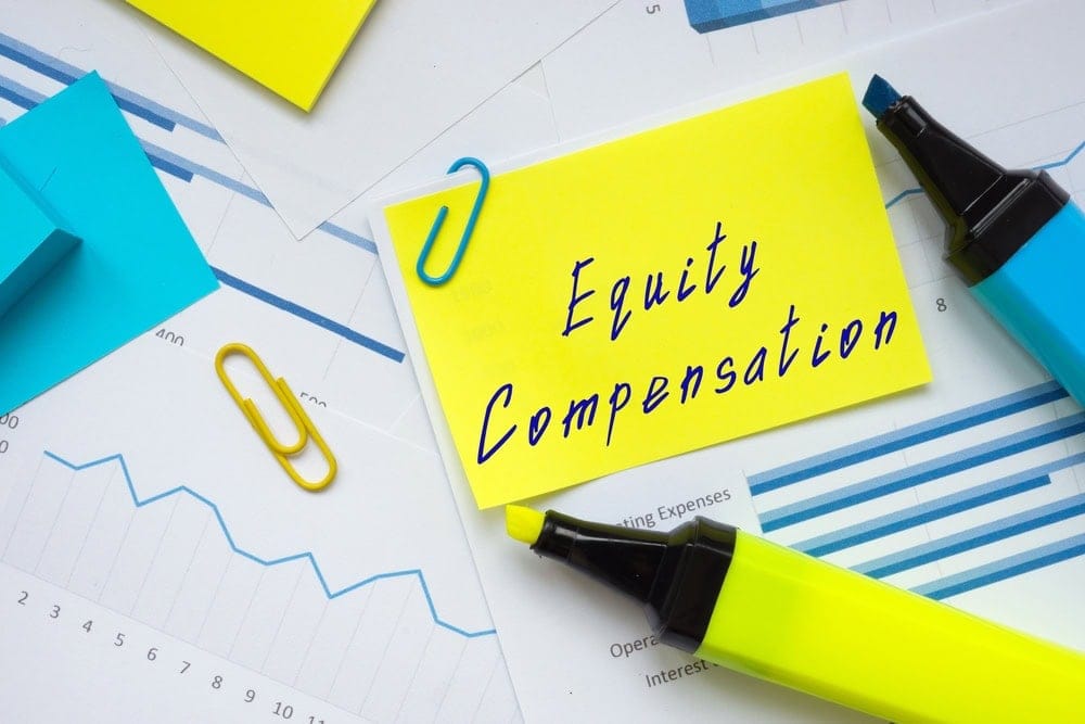 A yellow note labeled "Equity Compensation" with charts, blue and yellow highlighters, and paper clips on a desk.
